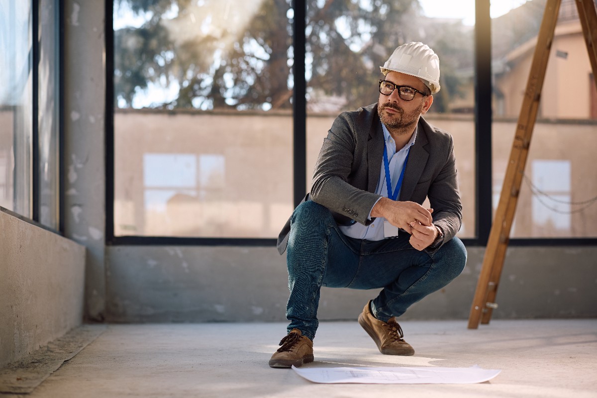 Pensive Architect Working On Blueprints At Construction Site.